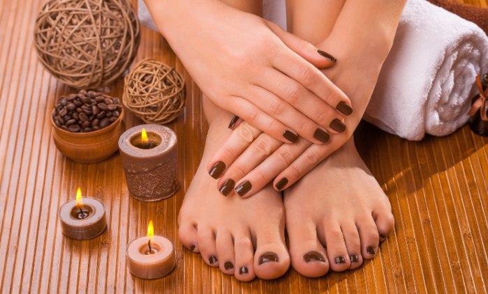 A pedicure set up on warm wood beside lit candles, the kind we bring to your home