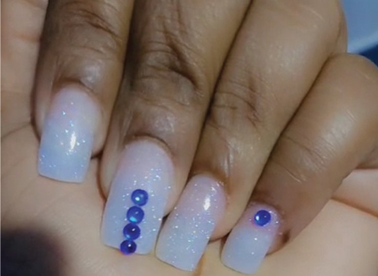 A pale blue ombre gel manicure with gem detail